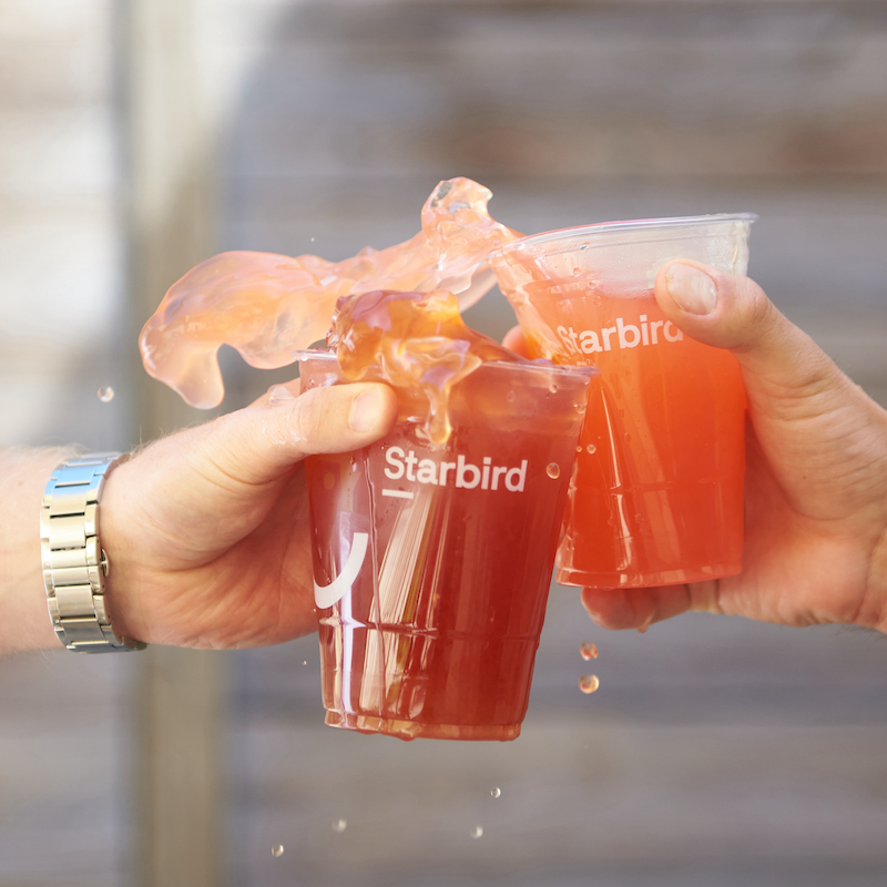 Two hands toasting with Starbird Chicken soda