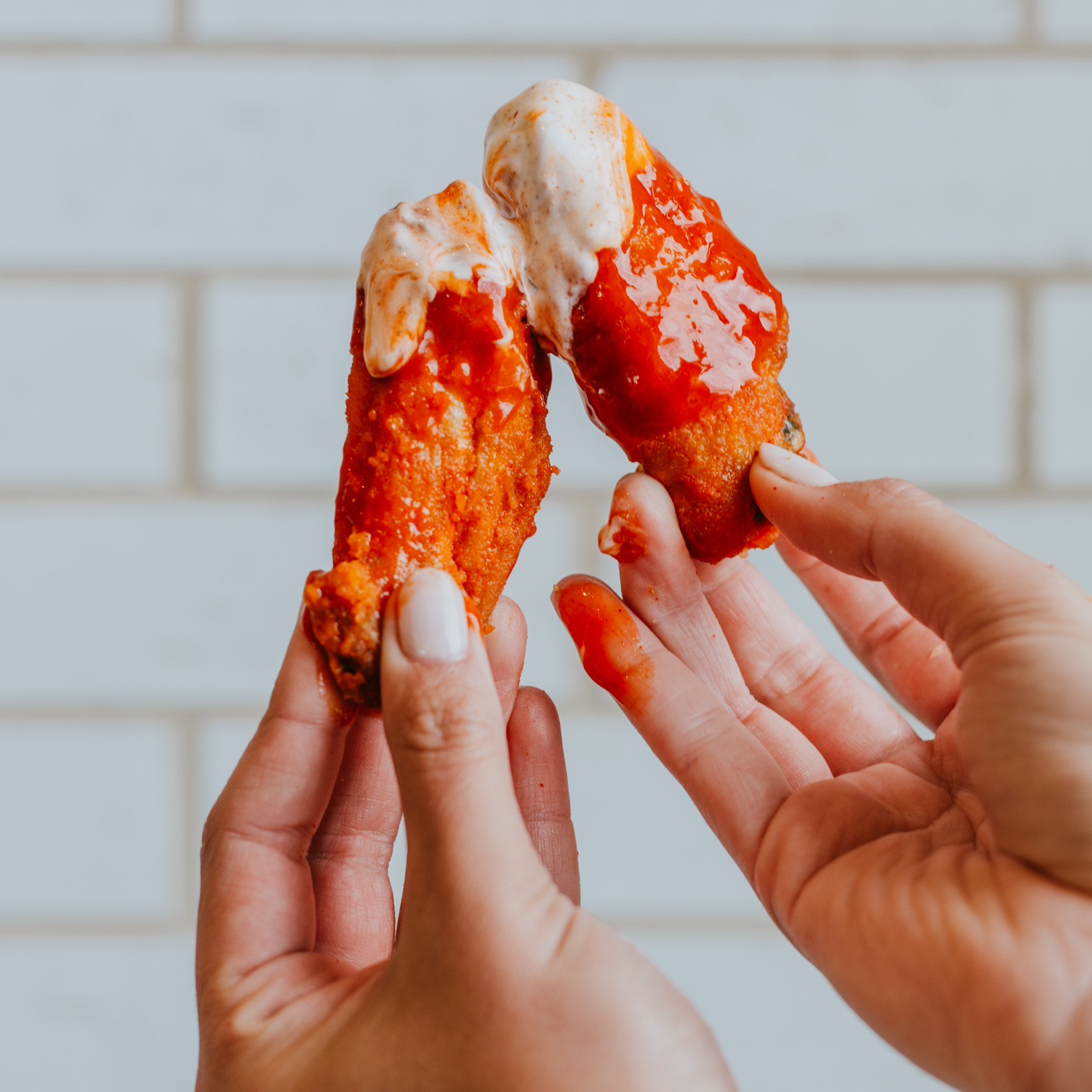 Two hands holding up Starbird Chicken wings